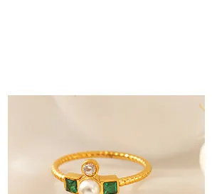 Detail van 18k gouden ring met witte parel, groene zirkonia en getextureerde band