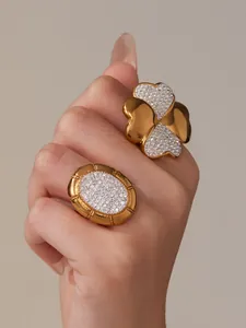 Detail of 18k gold plated four-leaf flower and oval ring with sparkling crystals on hand
