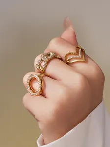 Detailansicht von drei vergoldeten Ringen mit Zirkonia-Herz und Panzerkettendesign