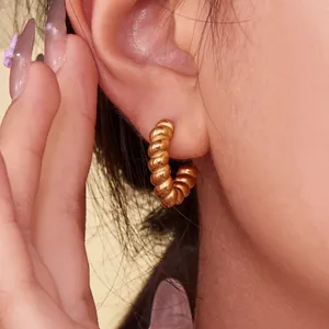 Polished 18k gold plated twisted hoop earrings with a textured spiral design on model
