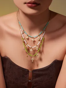 Dreilagige böhmische Perlenkette mit goldenen religiösen Anhängern am Modell