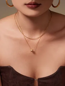 Détail de colliers superposés et créoles plaqués or 18 carats sur modèle femme