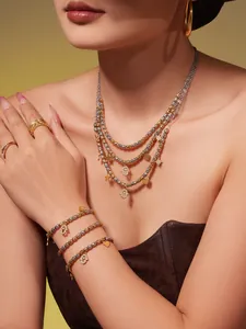 Gros plan des colliers Hamsa superposés et bracelets en perles aux charmes dorés