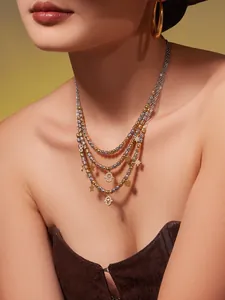 Détail d'un collier multicouche avec perles dorées et argentées et divers pendentifs