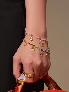 Detailansicht von Edelstein-Perlenarmbändern mit goldenen Herzanhängern am Handgelenk