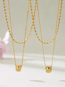 Détail de colliers doubles couches plaqués or 18 carats avec pendentifs cylindriques