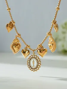 Macro detail of 18k gold beads necklace with heart charms and Virgin Mary pendant