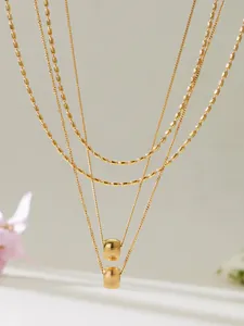 Vue détaillée des colliers multicouches plaqués or 18k avec pendentifs cylindriques