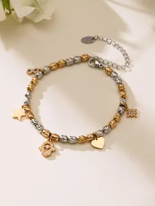 Détail d'un bracelet à breloques bicolore avec des pendentifs étoile, cœur et infini