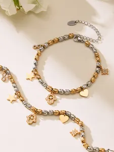 Détail d'un bracelet perlé avec breloques main de Hamsa, cœur et étoile en or et argent