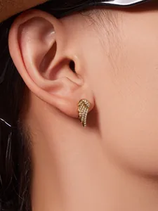 Close-up of gold angel wing stud earrings with sparkling pavé zircons worn by a model