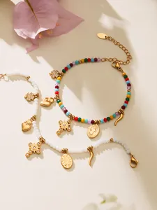Detail von Perlenarmbändern mit goldenen religiösen Anhängern und Kristallen