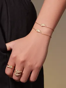 Detail of 18k gold-plated angel wing jewelry set with zircons on a model's hand