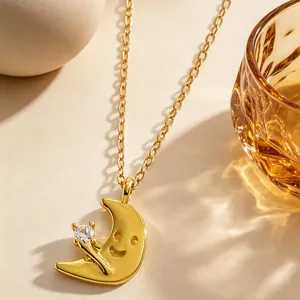 Primo piano della collana a mezzaluna dorata con faccina sorridente e dettaglio zircone