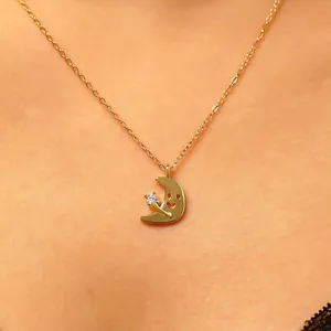 Primo piano di un'elegante collana con pendente a mezzaluna dorata con zircone sul collo
