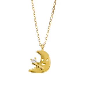 Dettaglio di una collana a luna placcata oro con faccina sorridente e stella in zircone