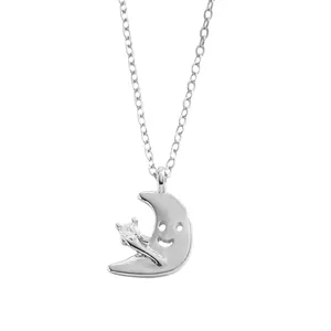 Primo piano di una collana a mezzaluna argentata con faccina sorridente traforata e zircone