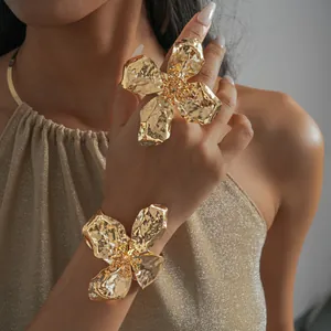 Detailed shot of oversized gold wrinkled flower ring and matching cuff bracelet.