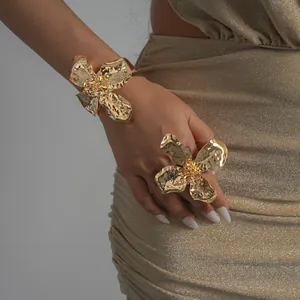 Close-up of metallic hammered flower ring and bracelet set on a model