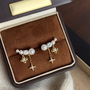 Dettaglio degli orecchini con fiori e perle placcati oro 18k in una scatola marrone