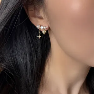 Dettaglio di eleganti orecchini placcati oro 18k con perle e nappe floreali su modella