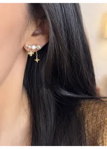 Dettaglio di eleganti orecchini placcati oro 18k con perle e ciondoli floreali
