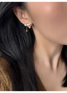 Dettaglio di eleganti orecchini placcati oro con fiori e perle su una modella