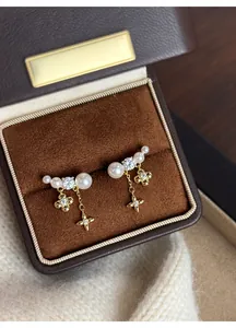 Dettaglio squisito di orecchini con perle placcati oro 18k con ciondoli a fiore e stella