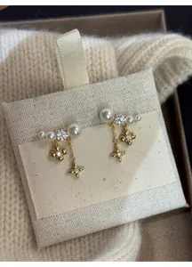 Dettaglio di eleganti orecchini a nappa placcati oro 18k con perle e ciondoli a forma di fiore