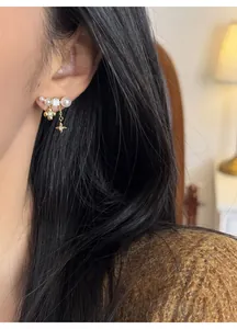 Primo piano di eleganti orecchini a fiore e perla placcati in oro 18k su un modello