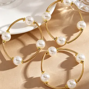 Detailansicht von drei goldenen elastischen Armbändern mit eleganten weißen Perlen