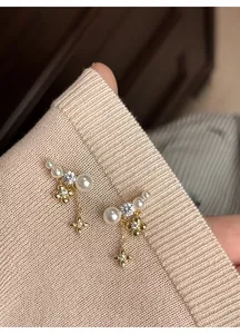 Dettaglio degli orecchini a fiore placcati oro 18k con perle eleganti e nappe a stella