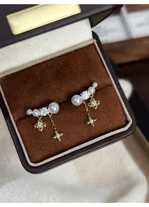 Primo piano di orecchini con nappa a fiore e perle placcati in oro 18k in una scatola regalo