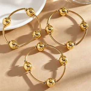 Detailansicht von drei goldenen minimalistischen stapelbaren Perlenarmbändern im Set