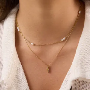 Detailaufnahme einer zweilagigen, 18 Karat vergoldeten Perlenkette am Hals getragen