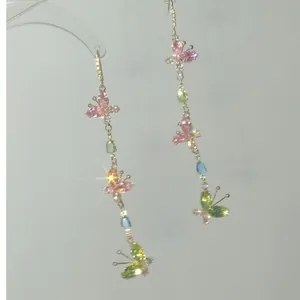 Eleganti orecchini lunghi con nappe e farfalle in zircone colorato dallo stile scintillante.
