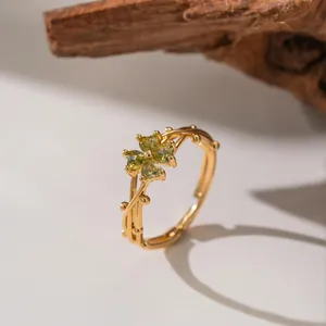 Close-up of golden adjustable ring with green heart-shaped gems in flower design