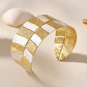 Bracciale rigido a scacchi oro e bianco con trama a onde su sfondo con conchiglie marine