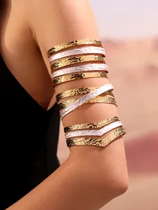 Detail of multi-layer gold and silver textured arm cuffs worn on model in desert light