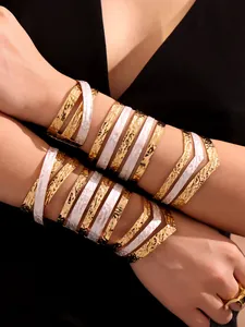 Dettaglio di bracciali multistrato placcati oro 18k con smalto bianco e trama martellata