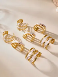 Detail of layered gold and white enamel open bangles with hammered metal texture