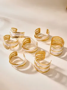 Dettaglio di bracciali multistrato in acciaio inossidabile placcato oro 18k martellato
