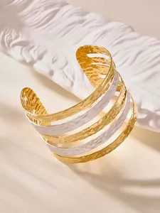 Dettaglio di un bracciale rigido a più strati con texture martellate oro e argento