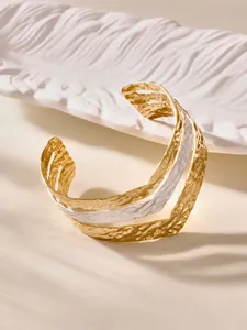 Detail of multi-layer waved gold and silver cuff bracelet with hammered texture