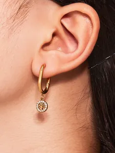 Gros plan de boucles d'oreilles Arbre de Vie dorées serties de zircons sur un mannequin