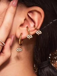 Détail des boucles d'oreilles arbre de vie dorées avec zircons sur une oreille