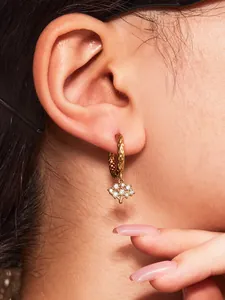 Détail de boucles d'oreilles arbre de vie dorées avec zircons et texture martelée