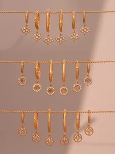 Détail de boucles d'oreilles arbre de vie dorées avec zircons sur fond rose