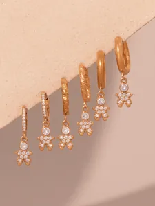 Macro shot of gold-plated astronaut earrings with 5A zircons on a beige felt surface