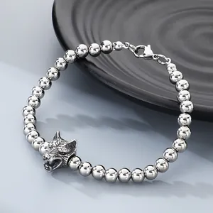 Detailed macro shot of a stainless steel beaded bracelet featuring a wolf head charm.